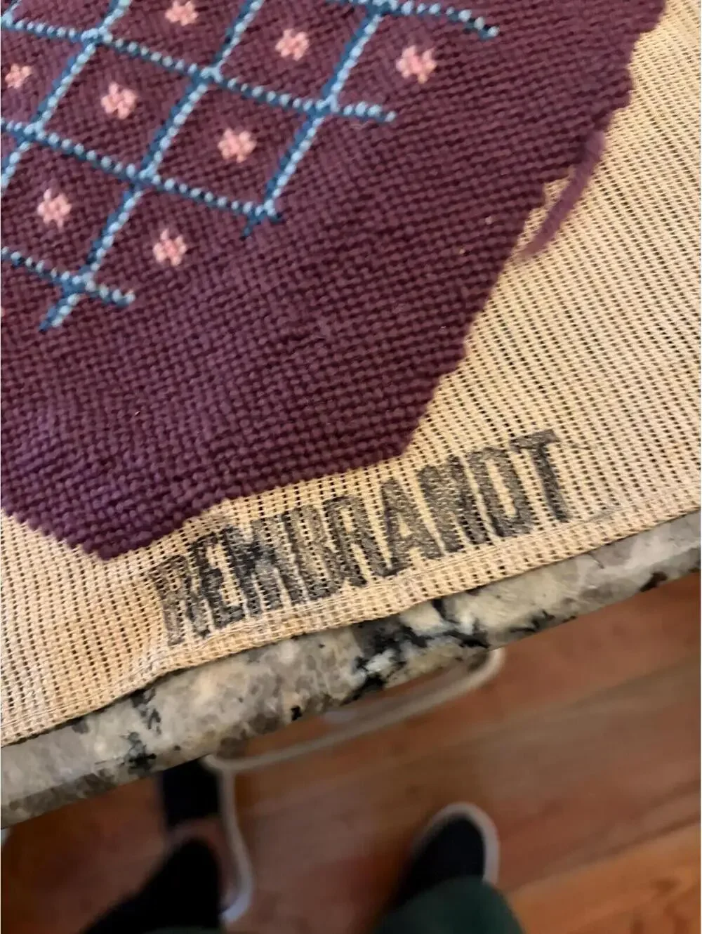 needlepoint tapestry featuring a wreath and geometric pattern.